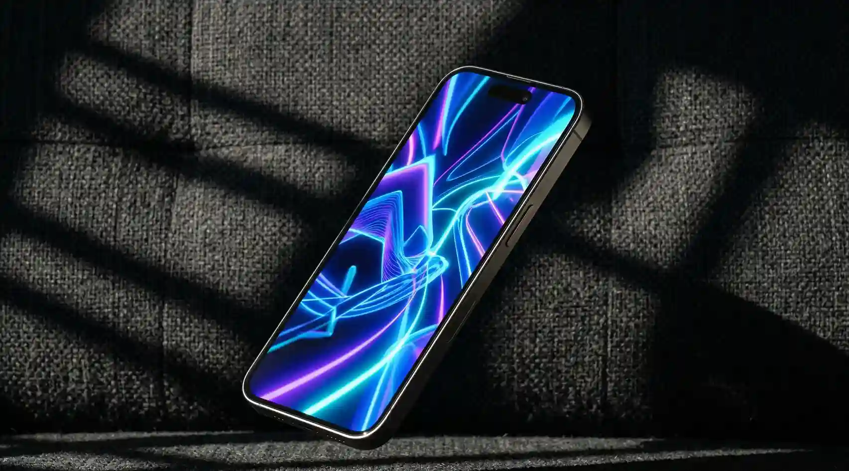 cinematic hero shot of a smartphone angled diagonally and floating over a dark charcoal-textured fabric. The screen displays a fluid, abstract 3D WebGL animation in vibrant neon blues and purples, featuring dramatic sunlight and sharp geometric shadows.