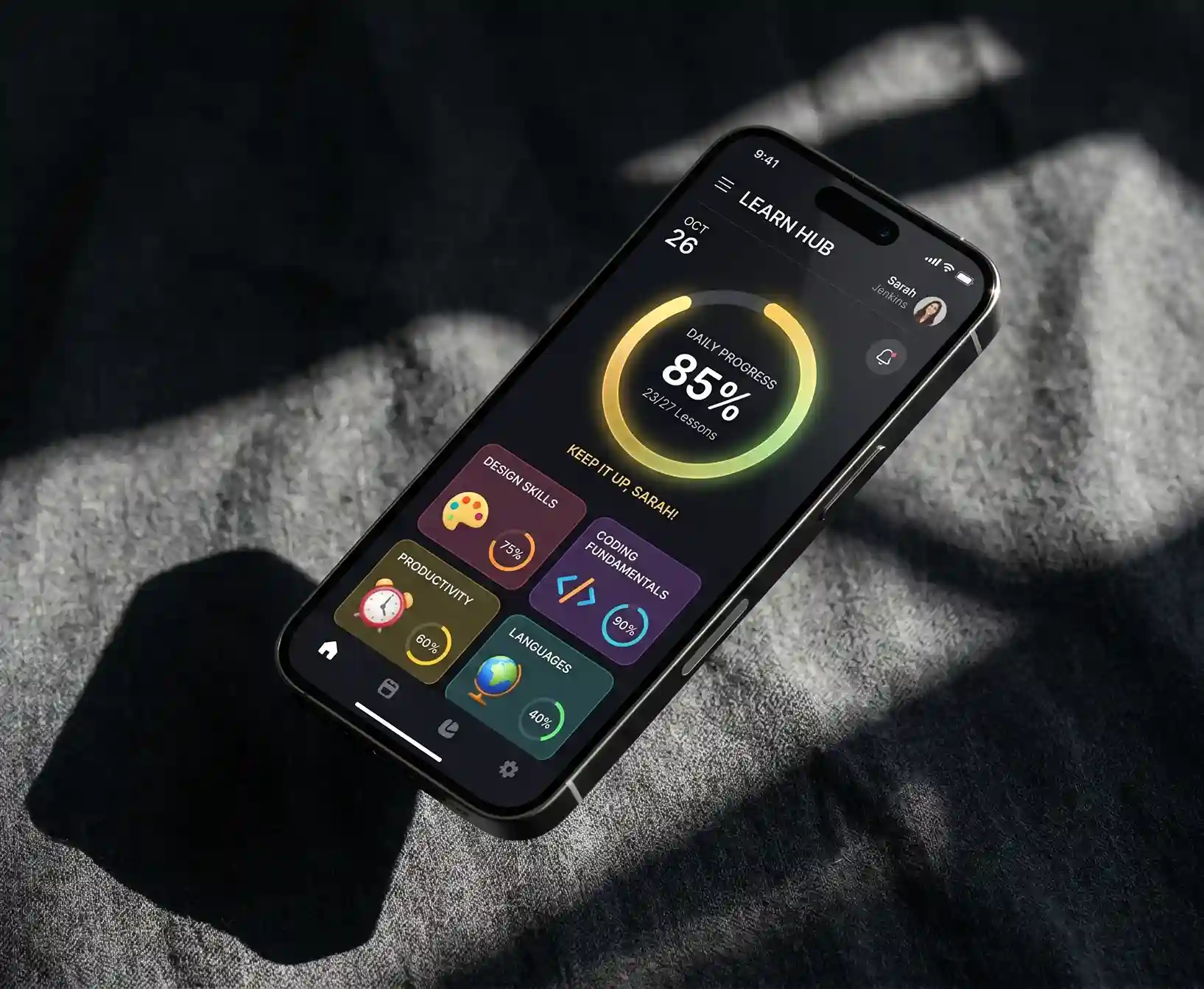 Cinematic hero shot of a smartphone floating over charcoal fabric showing a vibrant EdTech learning dashboard with progress rings.