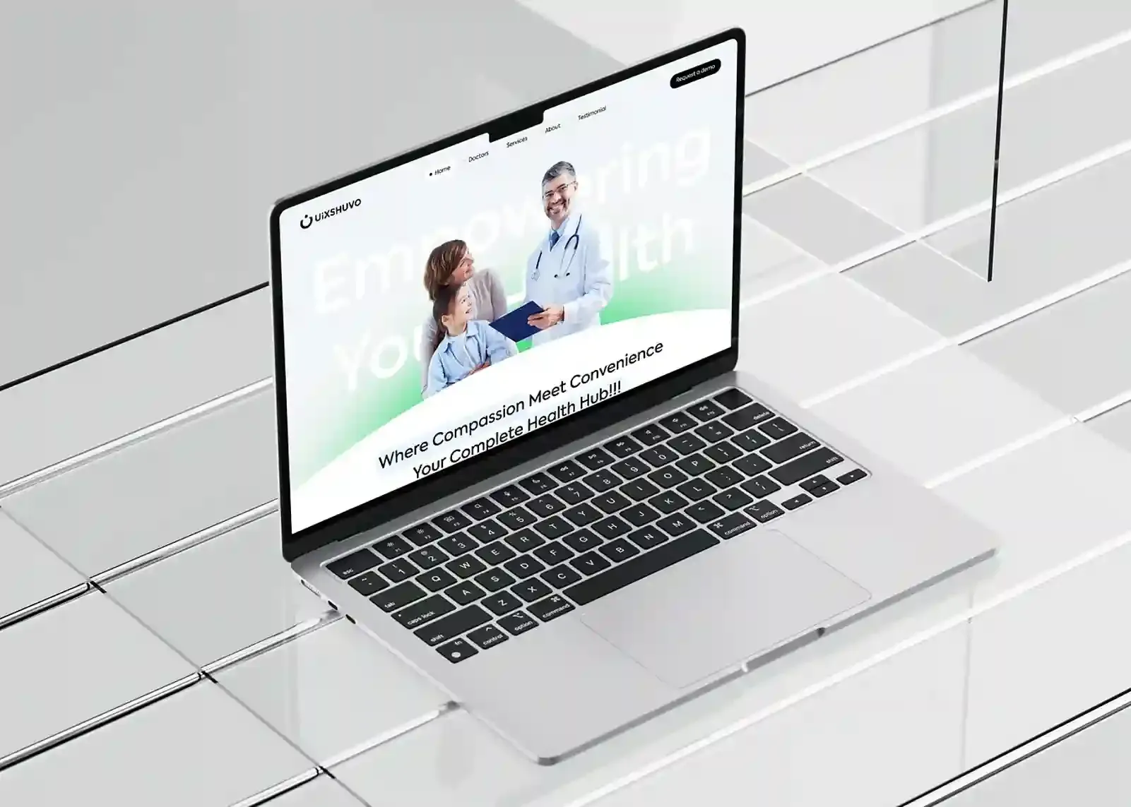 Laptop on a tiled glass surface displaying a healthcare website mockup titled "Empowering Your Health."