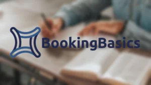 The corporate logo for "BookingBasics" in a bold, dark blue sans-serif font, positioned next to an abstract, interconnected four-pointed star icon in shades of blue. The logo is overlaid on a softly blurred, warm-toned background of a person writing in a notebook next to an open textbook.
