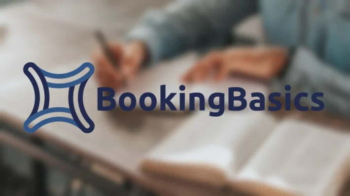 The corporate logo for "BookingBasics" in a bold, dark blue sans-serif font, positioned next to an abstract, interconnected four-pointed star icon in shades of blue. The logo is overlaid on a softly blurred, warm-toned background of a person writing in a notebook next to an open textbook.