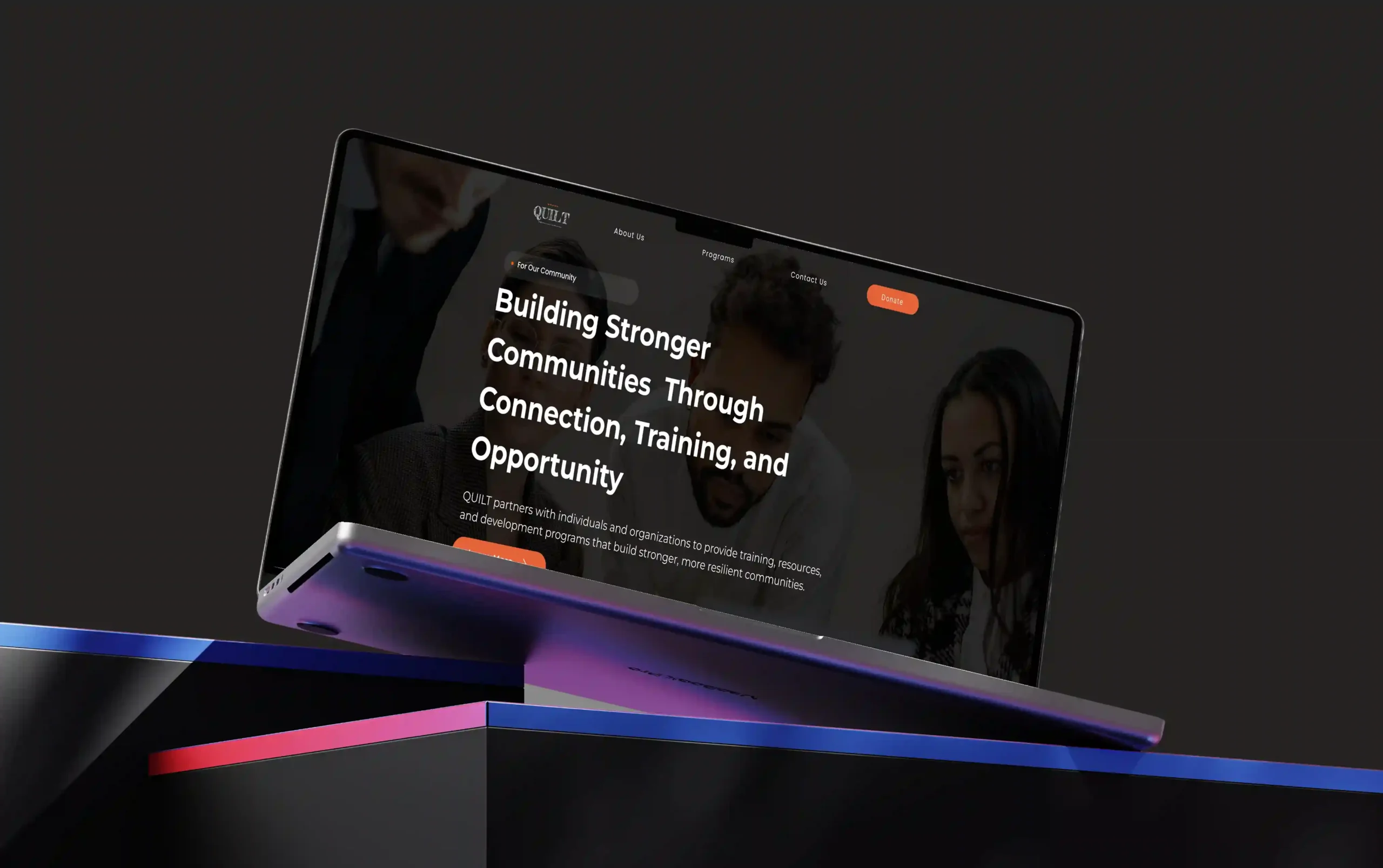 Mockup of the QUILT nonprofit website displayed on a floating laptop screen, featuring a modern dark-themed homepage focused on community connection, training, and opportunity.