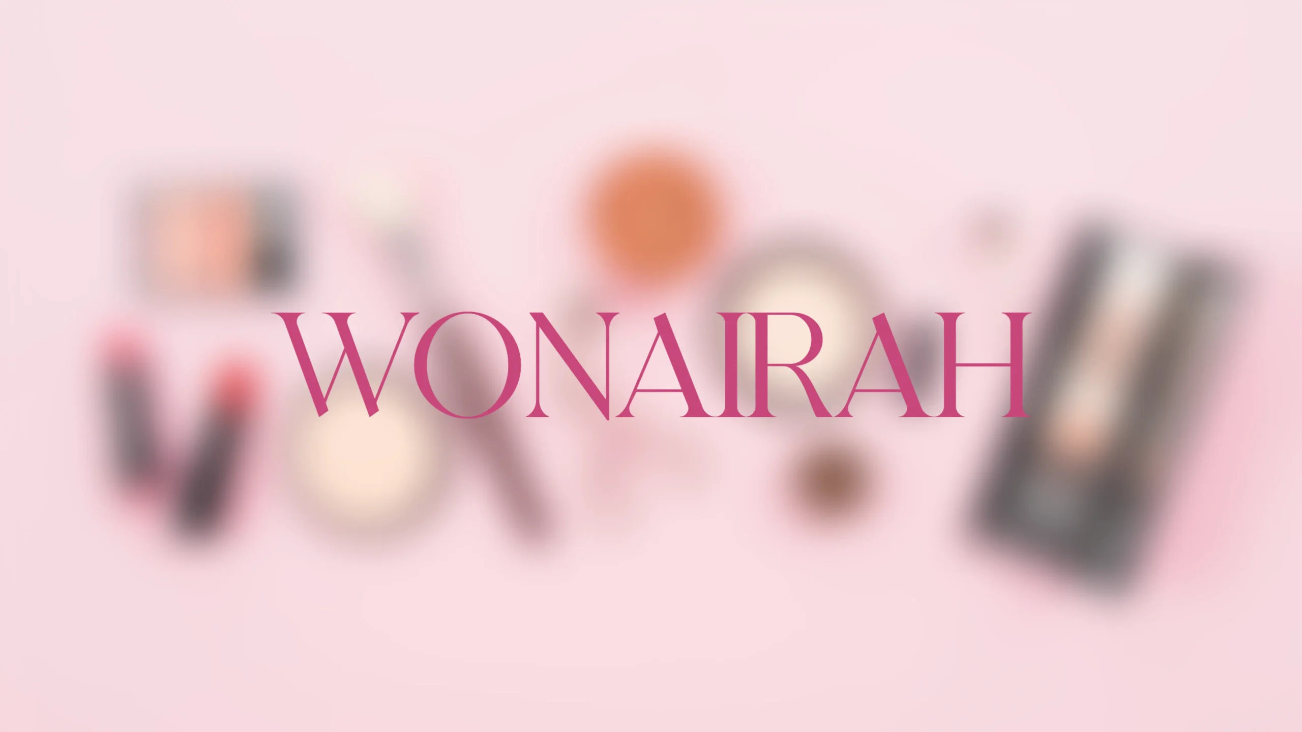 A soft pink background with blurred makeup and beauty products scattered around the edges, featuring the word ‘WONAIRAH’ prominently centered in elegant pink typography.